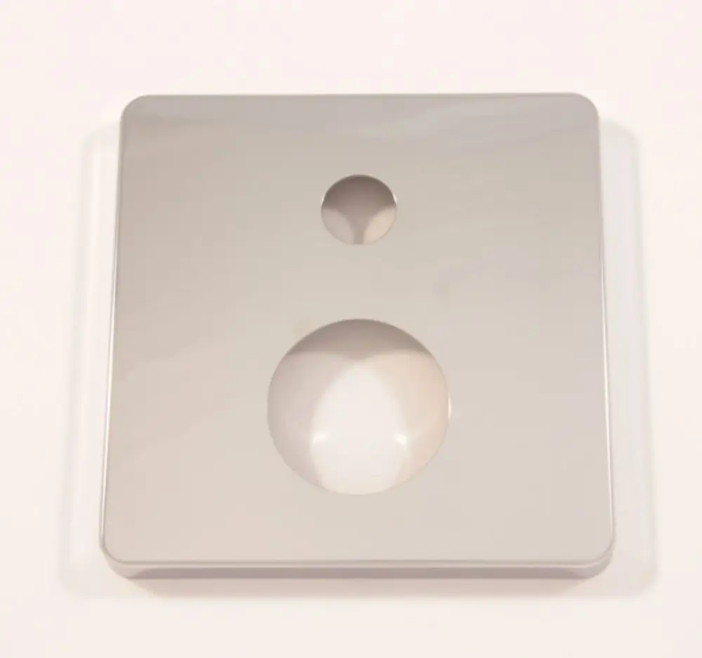 Quadratische Rosette aus Chrom von Ideal Standard mit zwei Öffnungen, einer runden und einer kleineren, auf glatter Oberfläche.